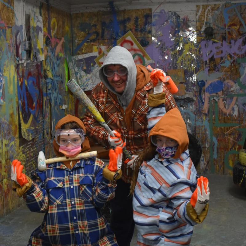 dad and two boys in full equipment having fun at unity rage room