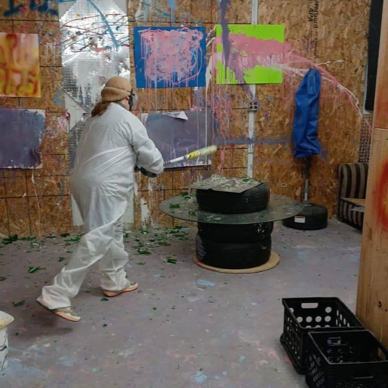 woman smashing stuff with a baseball bat at unity rage room